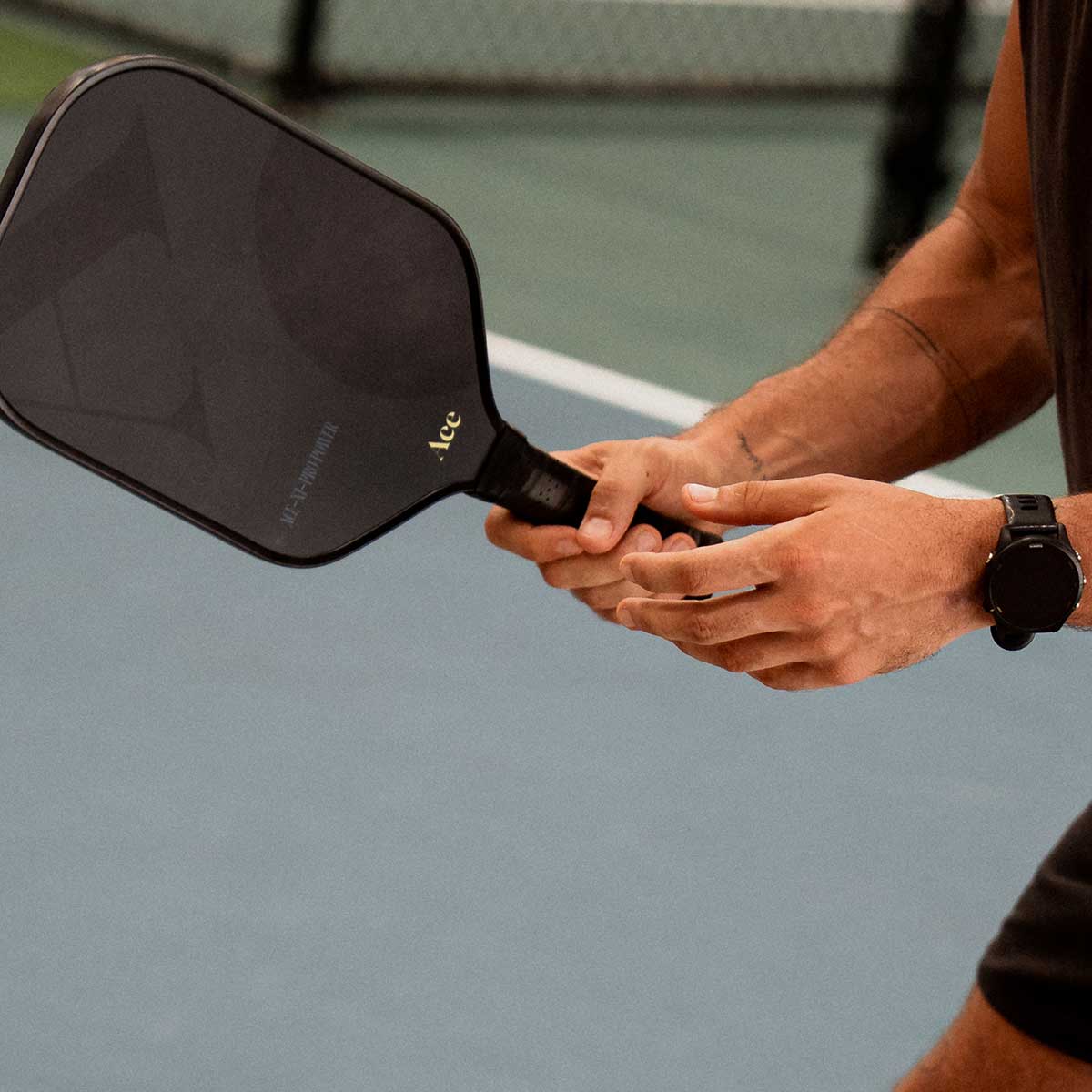 Person holding a pickleball paddle on a court