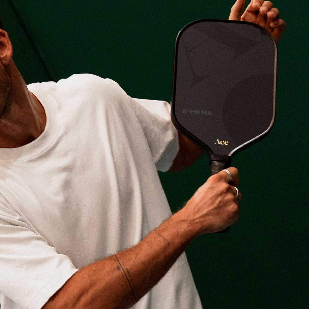 Person holding a pickleball paddle with a green background