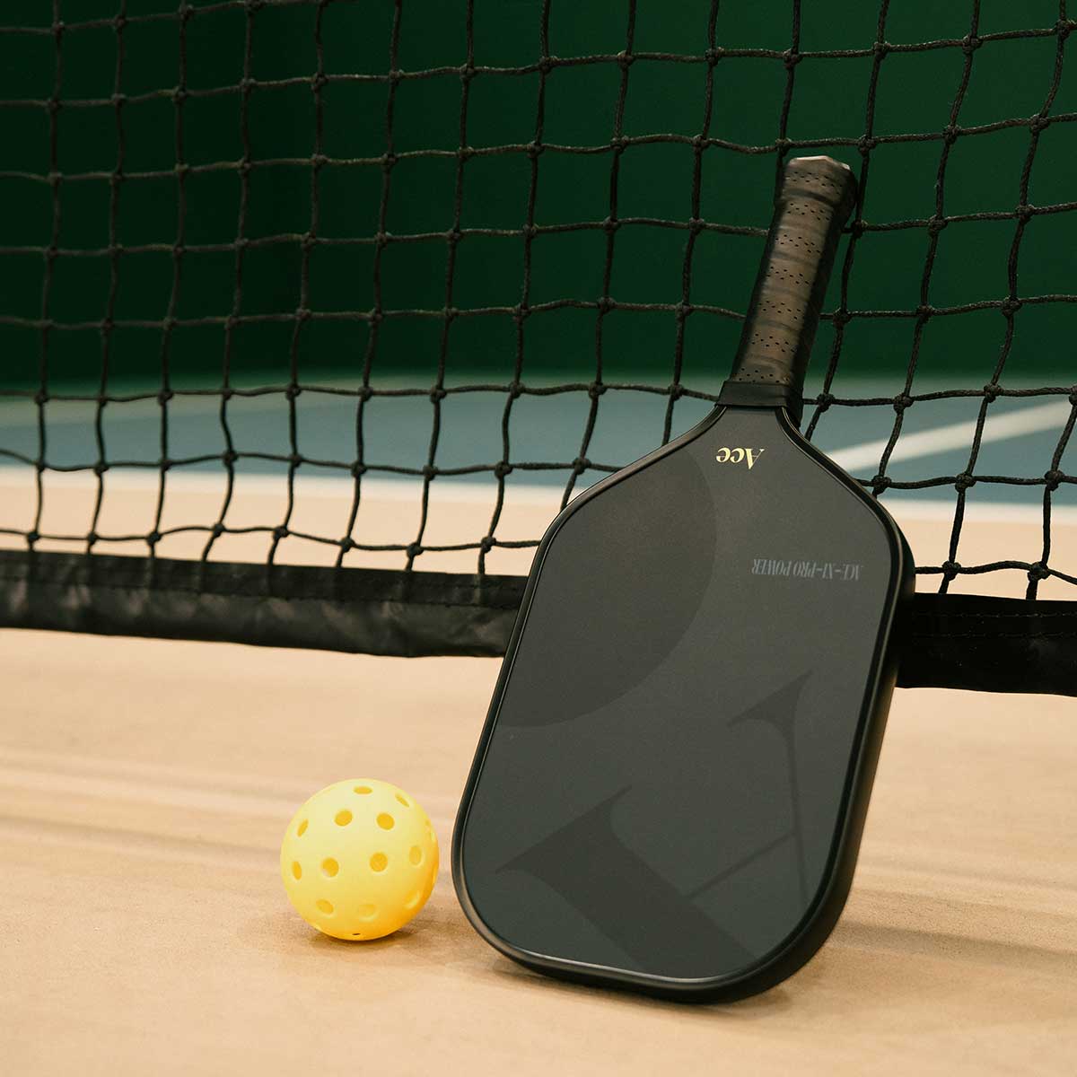 Pickleball paddle and ball on a court with a net in the background