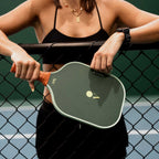 Person holding a pickleball paddle on a tennis court
