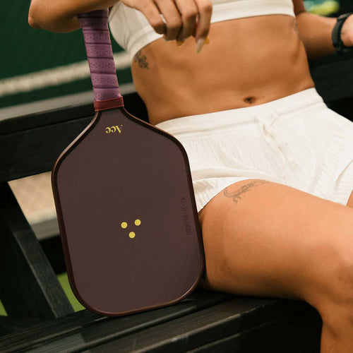 Person holding a pickleball paddle with a blurred background