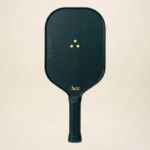 Black pickleball paddle with yellow text on a beige background