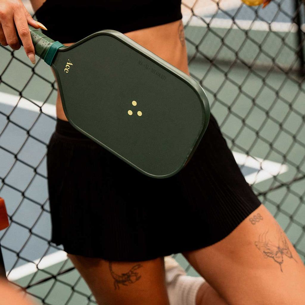 Person holding a green pickleball paddle on a court