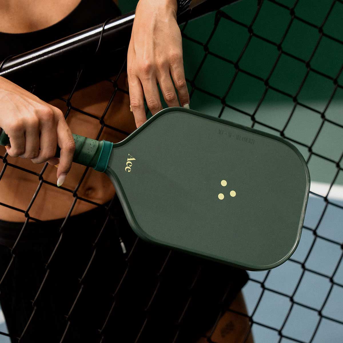 Person holding a green pickleball paddle on a court