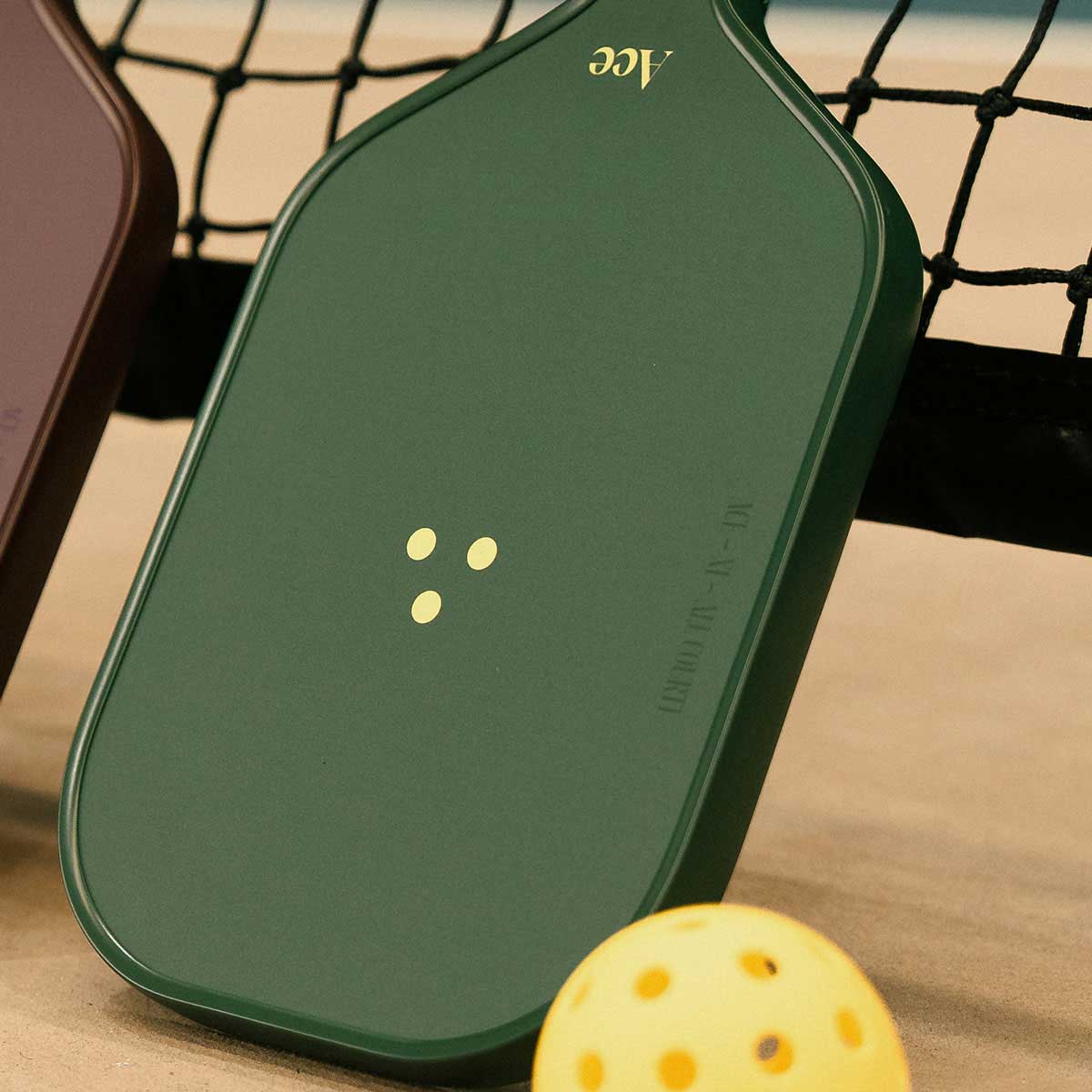 Green pickleball paddle with yellow dots on a beige surface, close-up view.